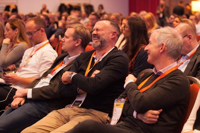 Conference attendees laugh at a speaker's joke